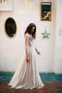 a woman wearing a white dress standing in front of a wall