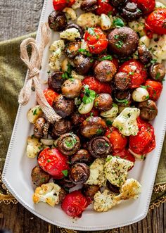 roasted tomatoes, mushrooms and other vegetables on a platter with a bow tied around the edge