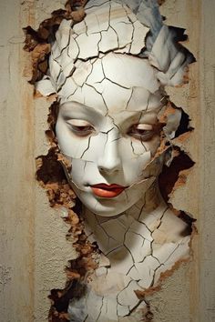 a woman's face is shown through the cracked wall