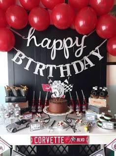 a birthday party with balloons, cake and decorations on a table in front of a sign that says happy birthday corvette