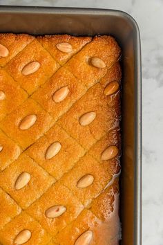 a square cake with almonds on top in a pan