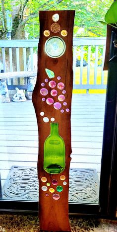 a green glass bottle sitting on top of a wooden tree trunk with circles and bubbles