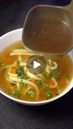 a bowl of soup with noodles, carrots and broth being gravy