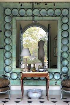 a mirror and two chairs in front of a table with a lamp on top of it