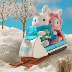 two stuffed animals are riding on a sled in the snow