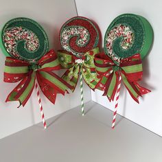 two candy lollipops decorated with green and red ribbons