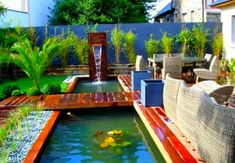 a small garden with a water feature in the center and patio furniture around it,