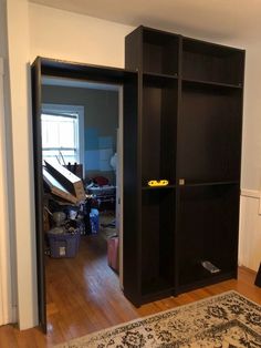 an empty room with a black bookcase in the corner and a rug on the floor