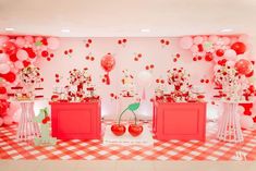 an image of a party setting with red and pink balloons on the wall, cherry boxes in the center