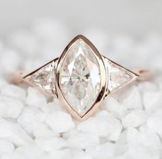 a ring with three pear shaped diamonds on top of it, surrounded by white rocks