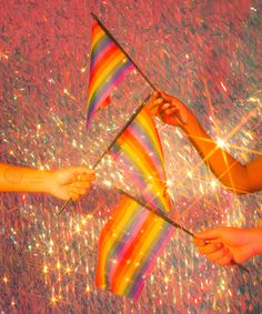 two people holding rainbow flags in front of fireworks