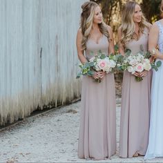 the bridesmaids are all dressed in long dresses and holding their bouquets together