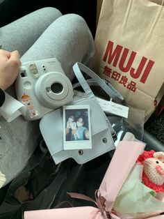 a person holding a camera next to a stuffed animal and other items on a chair