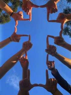 a group of people holding their hands together in the shape of a circle with fingers pointing up