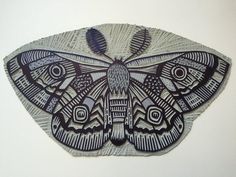 an intricately designed moth on a white wall