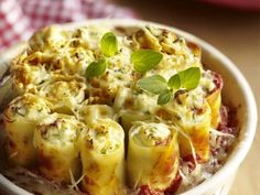 a white bowl filled with pasta covered in cheese and sauce on top of a wooden table