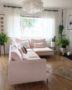 a living room filled with furniture and lots of white pillows on top of it's wooden flooring