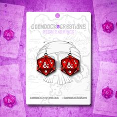 two red dice shaped earrings sitting on top of a purple background with other dices