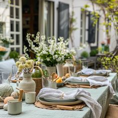 the table is set with plates, cups and vases filled with flowers on it