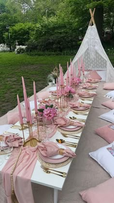 a long table is set with pink napkins and place settings for an outdoor party