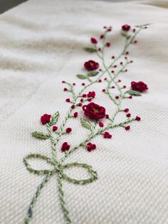 a close up of a piece of cloth with red flowers on it and green stems