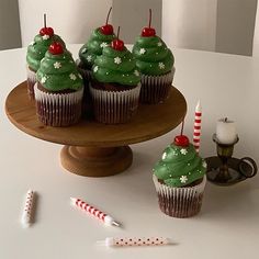 cupcakes decorated with green frosting and candy canes on a cake stand