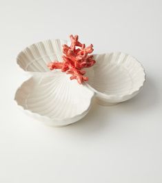 two white bowls with red flowers in them on a white tableclothed surface, one bowl is empty and the other has an orange flower