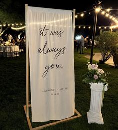 a white banner with the words it was always you on it in front of some string lights