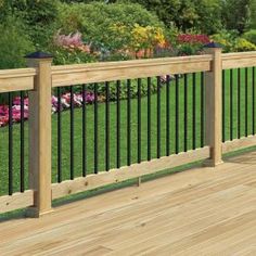 a wooden deck with black iron railing and flowerbeds in the backgroud