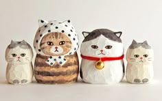 three cat figurines sitting next to each other on a white surface with a red ribbon around their neck