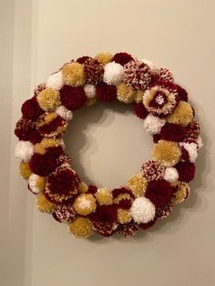 a wreath with pom - poms hanging on the wall