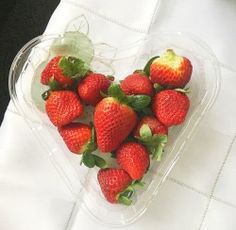 a heart shaped plastic container filled with strawberries