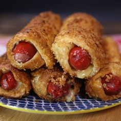 several hot dogs wrapped in bread on a blue and yellow plate with polka dot border