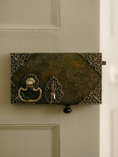 the door handle is attached to an ornately designed metal hook on a white door