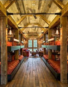 there are many bunk beds in this room with wood flooring and exposed beams on the ceiling