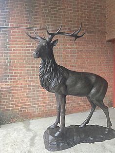 a statue of an antelope stands in front of a brick wall and door