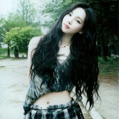 a woman with long black hair standing in the street