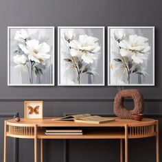 two white flowers are displayed on the wall above a wooden table in front of a gray wall