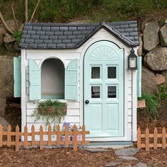 a small white and blue doll house next to a fence