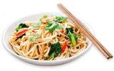 a white plate topped with noodles and veggies next to two chopsticks