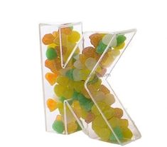 the letter k is made up of gummy bears in clear plastic containers on a white background