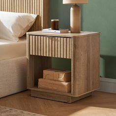 a nightstand with a lamp on top of it next to a bed