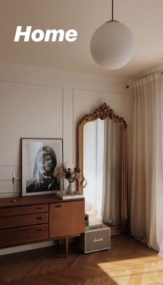 a living room with a mirror, dresser and lamp on the wall next to a window