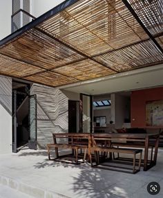 an outdoor dining area with wooden tables and benches under a bamboo covering over the table