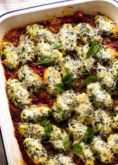 a casserole dish with spinach, cheese and sauce in it on a table