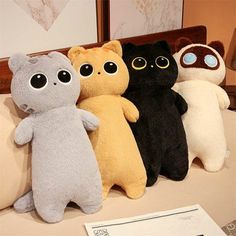 four stuffed animals sitting on top of a bed next to each other in different colors