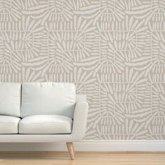 a white couch sitting in front of a wall with a plant pattern on it's side