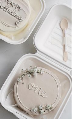 two cake tins with the words one on them and a spoon in each container