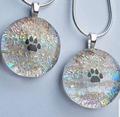 two pendants with an image of a dog's paw on the front and back