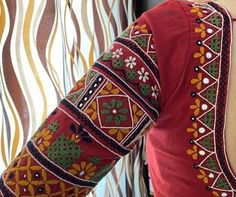 a woman's red top with green and yellow designs on the sleeves, back view